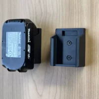 Makita 18v LXT battery holder mount shown next to a Makita battery for size comparison, black plastic with two screw holes