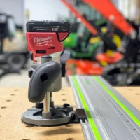 Milwaukee M18 plunge router mounted on a Festool guide rail, showing the adapter base and router head assembly from the side
