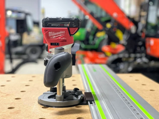 Milwaukee M18 plunge router mounted on a Festool guide rail, showing the adapter base and router head assembly from the side