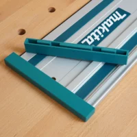 Teal protective caps mounted on each end of a Makita track saw rail