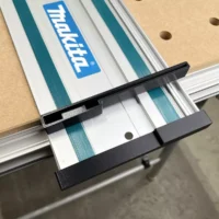 Black protective caps attached to each end of a Makita guide rail mounted on a track saw, with friction-fit design visible