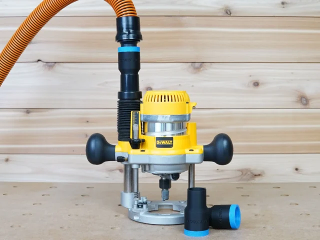 Black 1-1/4 inch hose adapter with blue ring linking an orange hose to a DeWalt plunge router dust port