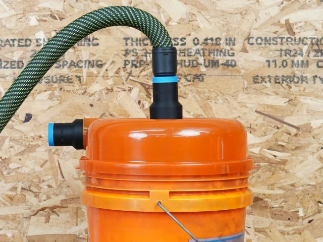 Two black 27mm hose adapters with blue bands on an orange Dustopper cyclone lid, one joined to a braided hose