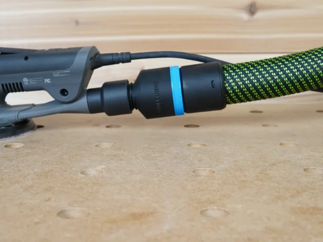 Black 36mm hose adapter with blue ring linking a green extractor hose to a 3M Xtract sander dust port