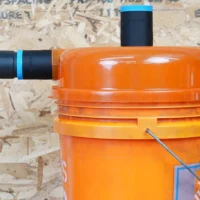 Two black 36mm hose adapters with blue rings on a Dustopper cyclone separator, one joined to a vac hose