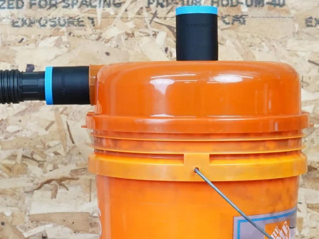 Two black ToolCurve 1-7/8 inch hose adapters with blue rings on a Dustopper separator lid, one with hose attached