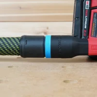 Black hose adapter with blue band attached to green-and-black braided hose and Milwaukee M18 red sander