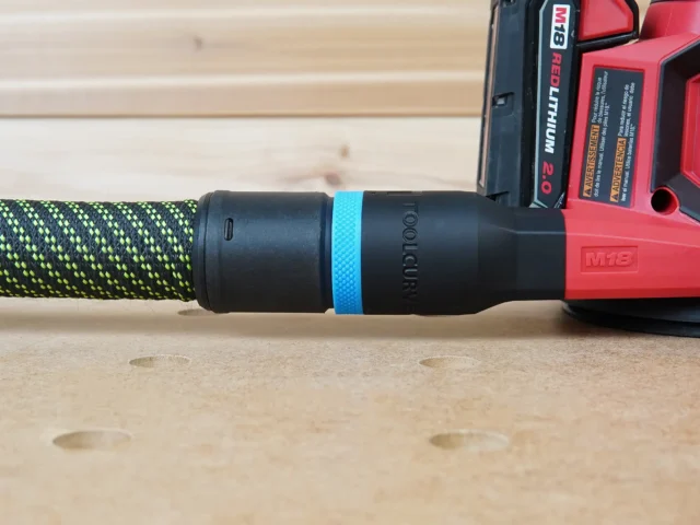 Black hose adapter with blue band attached to green-and-black braided hose and Milwaukee M18 red sander
