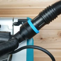 Black ToolCurve 1-7/8 inch hose adapter with blue ring joining a vacuum hose to a Makita miter saw port
