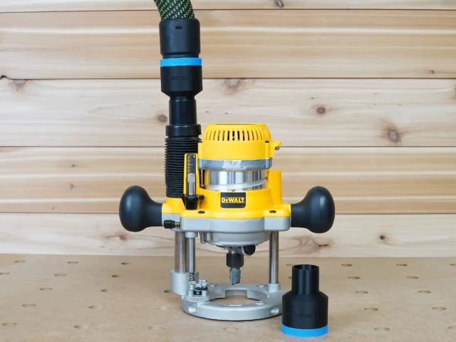 Black 36mm hose adapter with blue band on a DeWalt plunge router dust port, second adapter beside it