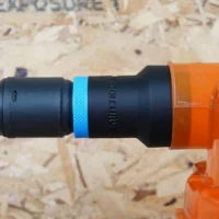 Black hose adapter with blue band attached to orange Dustopper cyclone separator and green-and-black braided hose