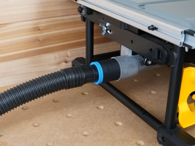 Black hose adapter with blue collar joining a 1-7/8 inch vacuum hose to a DeWalt table saw's rear dust port