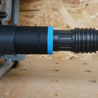 Black ToolCurve 1-7/8 in hose adapter with blue band joining a ribbed vacuum hose to a SKIL table saw dust port