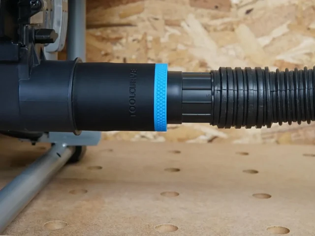 Black ToolCurve 1-7/8 in hose adapter with blue band joining a ribbed vacuum hose to a SKIL table saw dust port