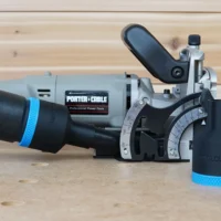 Black ToolCurve 36mm hose adapter with blue band fitted to the dust port of a Porter Cable 557 plate joiner, second adapter beside it