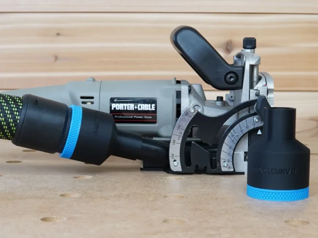 Black ToolCurve 36mm hose adapter with blue band fitted to the dust port of a Porter Cable 557 plate joiner, second adapter beside it