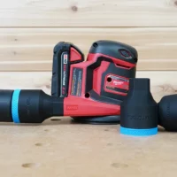 Black 36mm hose adapter with blue ring joining a green hose to a Milwaukee M18 sander, second adapter beside it