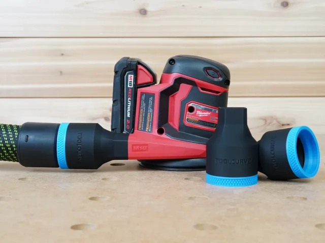Black 36mm hose adapter with blue ring joining a green hose to a Milwaukee M18 sander, second adapter beside it
