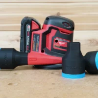 Black ToolCurve 1-7/8 inch hose adapter with blue trim in front of a Milwaukee M18 sander, plus a second adapter