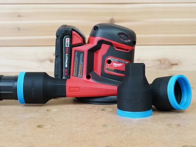 Black ToolCurve 1-7/8 inch hose adapter with blue trim in front of a Milwaukee M18 sander, plus a second adapter