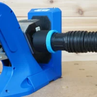 Blue 1-7/8 inch hose adapter joining a black ribbed vacuum hose to the dust port of a Kreg 720 jig