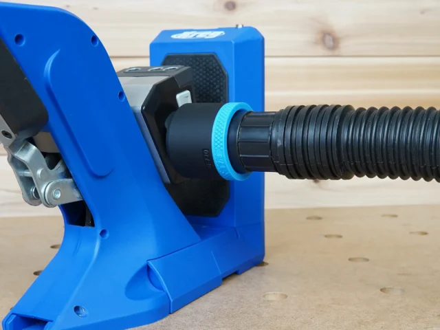 Blue 1-7/8 inch hose adapter joining a black ribbed vacuum hose to the dust port of a Kreg 720 jig