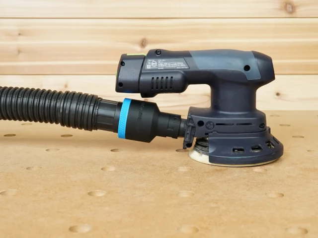 Black 1-7/8 inch hose adapter with blue ring joining a ribbed hose to the 27mm port of a Festool ETSC 125 sander