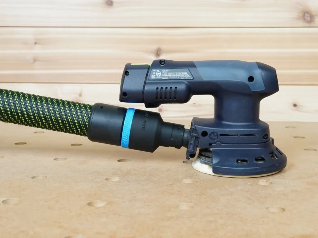 Black 36mm hose adapter with blue band linking a braided hose to the 27mm port on a Festool ETSC 125 sander
