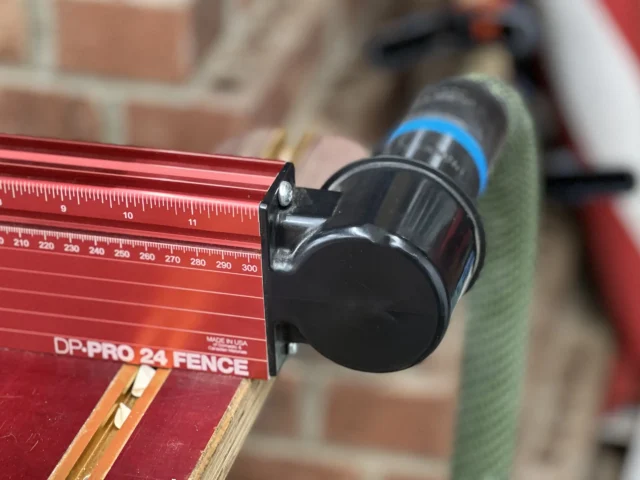 Black hose adapter mounted on red Woodpeckers DP-PRO 24 fence dust port with blue hose attached
