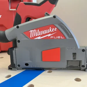 Red arbor dust cover snapped onto the side of a Milwaukee M18 FUEL track saw resting on a blue track