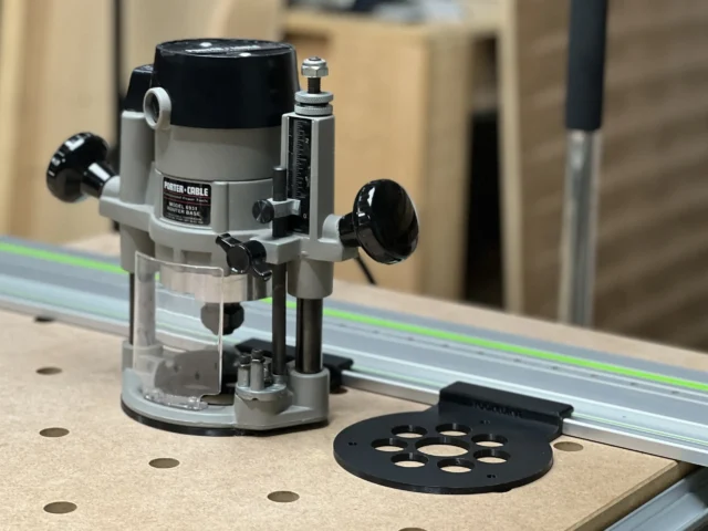 Porter Cable 690 router mounted on a Festool guide rail with a black ToolCurve adapter plate on the work surface