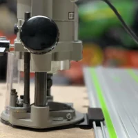 Porter Cable 690 router mounted on a gray adapter base connected to a green Festool track rail
