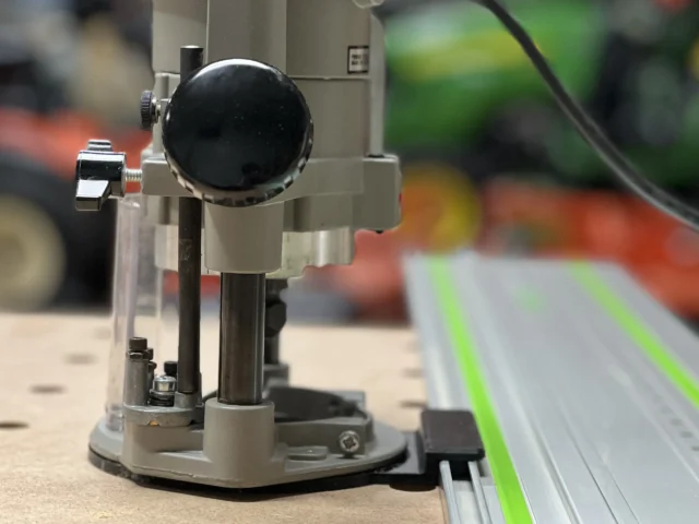 Porter Cable 690 router mounted on a gray adapter base connected to a green Festool track rail