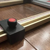 Black parallel guide carriage with red knob positioned on paired brass Milwaukee T-track rails with measurement scale