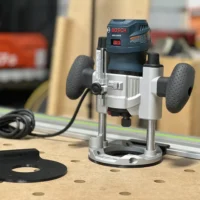Bosch PR011 & PR111 plunge router adapter mounted on a Bosch Colt router with guide rail, showing white aluminum base plate and black sub-base connector