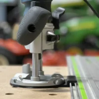 Bosch PR111 plunge router base attached to guide rail adapter mounted on track saw rail with green edge visible