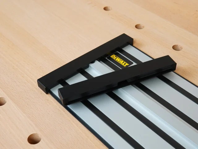 Black protective caps mounted on both ends of a Dewalt track saw rail, shown on a wooden workbench