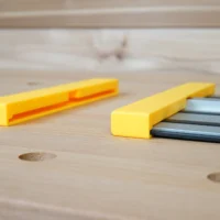 Two yellow Dewalt guide rail protective caps on wood surface; one shows interior channel detail, the other seated on dark aluminum track saw rail