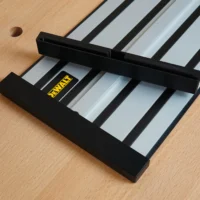 Black plastic protective caps mounted on the ends of a Dewalt track saw rail, shown resting on a wooden workbench