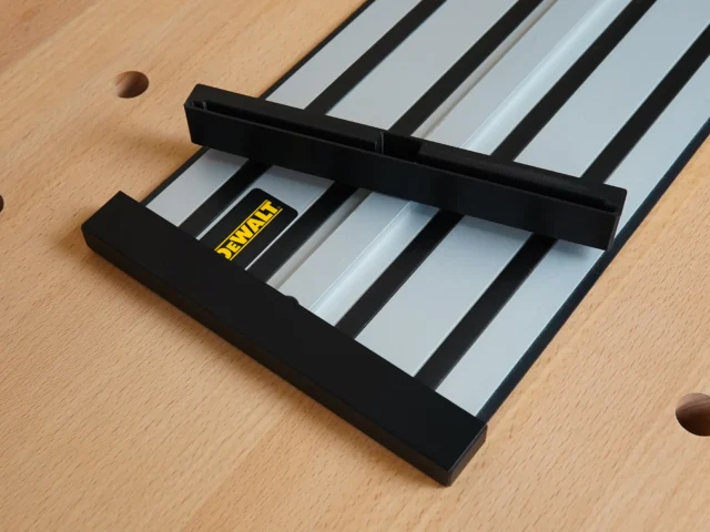 Black plastic protective caps mounted on the ends of a Dewalt track saw rail, shown resting on a wooden workbench