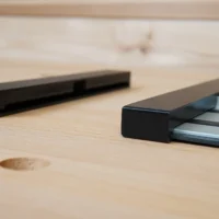 Two black Dewalt guide rail protective caps on a wooden surface, one shown alone and one slid onto an aluminum rail.