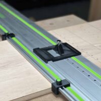 Black LR32 router adapter with knob mounted on a Festool LR32 guide rail, two drop stops set along the track