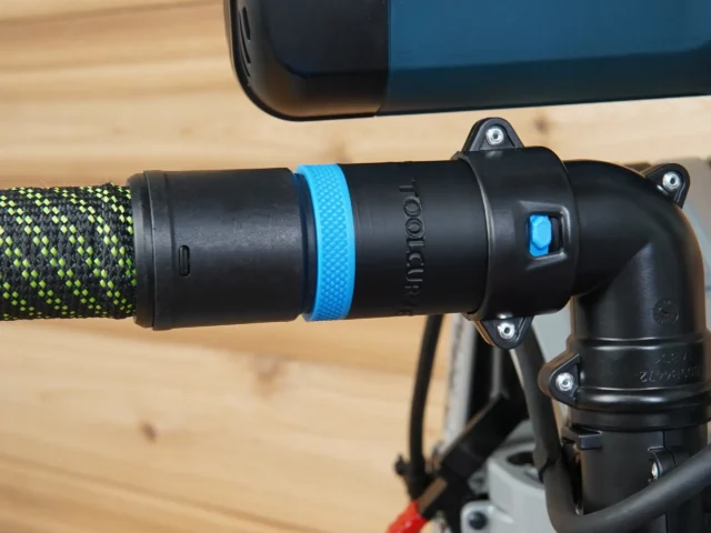 Black hose adapter with blue band attached to Bosch glide miter saw dust port, connected to green and black braided hose