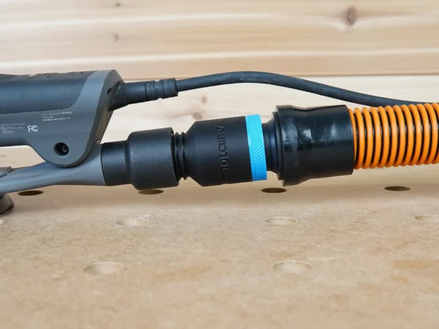 Black ToolCurve 1-1/4 inch hose adapter with blue band joining a 3M Xtract sander's dust port to an orange hose