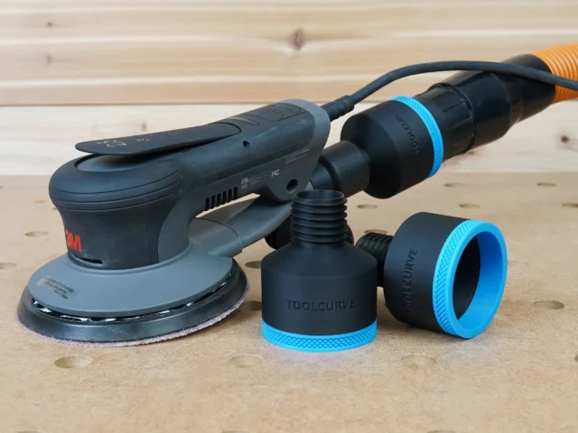 Black ToolCurve 2-1/2" hose adapter with blue ring beside a 3M Xtract sander, second adapter on hose
