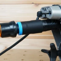 Black ToolCurve 1-1/4" hose adapter with blue collar joining an orange vac hose to a DeWalt miter saw dust port