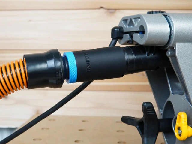 Black ToolCurve 1-1/4" hose adapter with blue collar joining an orange vac hose to a DeWalt miter saw dust port