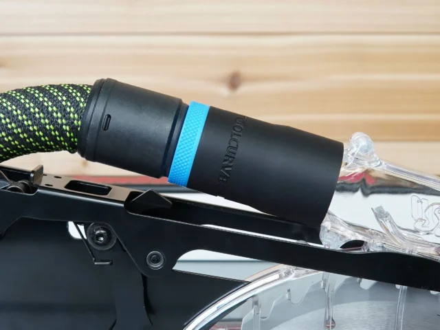 Black hose adapter with blue band installed on SawStop table saw blade guard, green and black braided hose attached