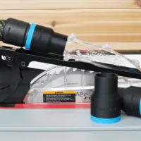 Black 36mm hose adapter with blue band joining an extractor hose to a SawStop jobsite saw blade guard, two spare adapters beside it