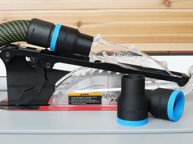 Black 36mm hose adapter with blue band joining an extractor hose to a SawStop jobsite saw blade guard, two spare adapters beside it
